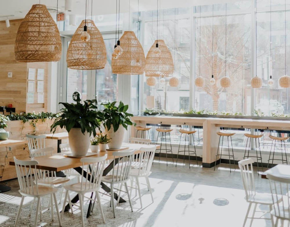 Μοντέρνα διακόσμηση εσωτερικού χώρου καφετέριας με μεγάλα φωτιστικά και φυτά