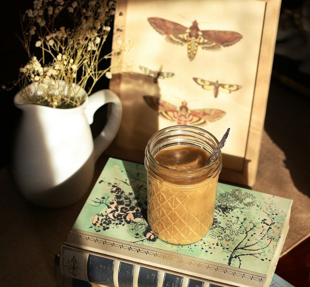 Καφές επάνω σε βιβλίο με κάδρο και ένα βάζο δίπλα σε vintage αισθητική