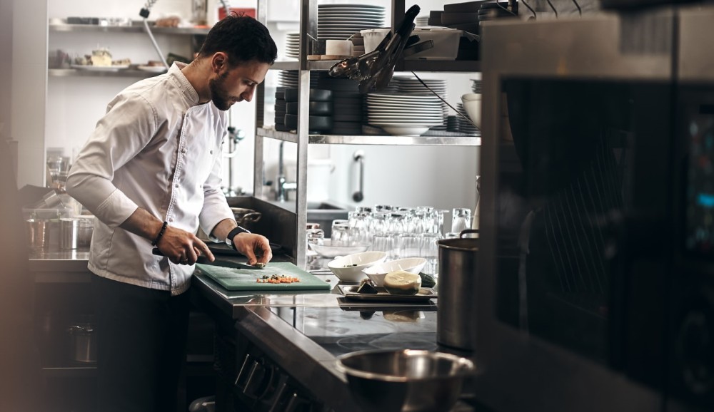 Άνδρας chef σε επαγγελματική κουζίνα με επαγγελματικό φούρνο μπροστά